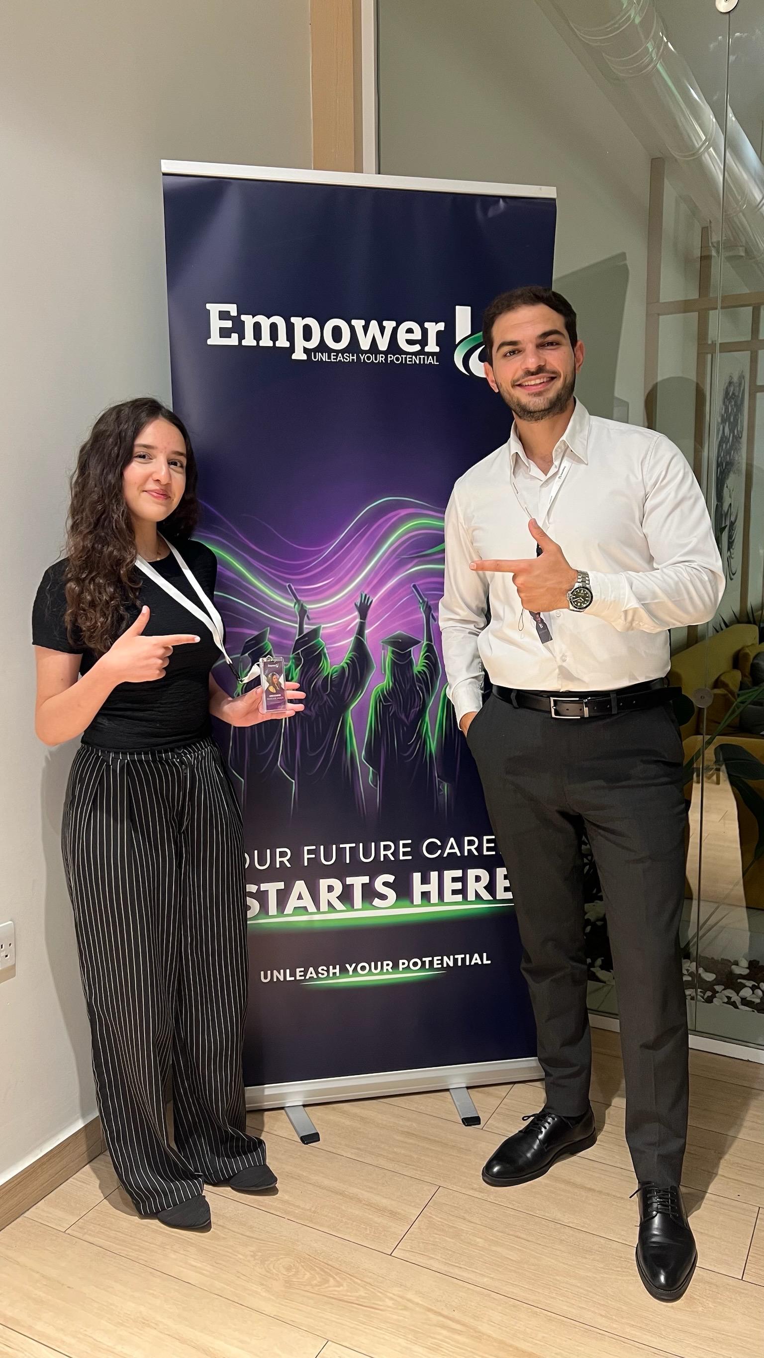 Two smiling Wave One participants next to the EmpowerU banner